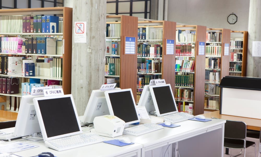 OPAC端末と本棚が写っている大学図書館